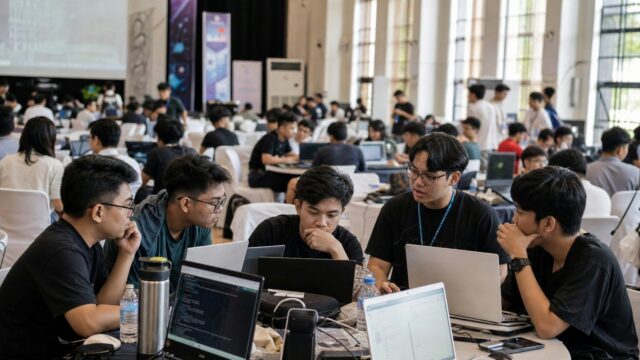 University students collaborating over laptops at a campus hackathon hall