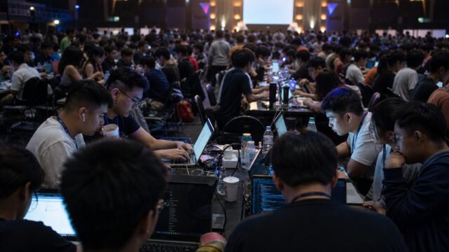 Student teams at long tables during a night hackathon in Manila