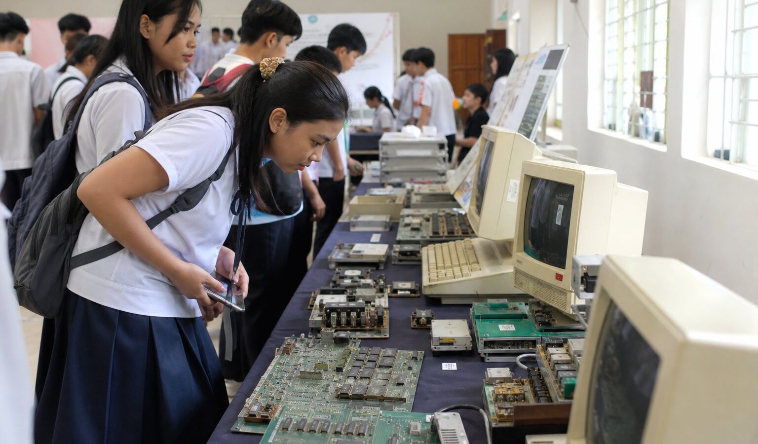 Students viewing vintage computers at a traveling technology exhibit in a school hall