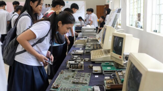 Students viewing vintage computers at a traveling technology exhibit in a school hall