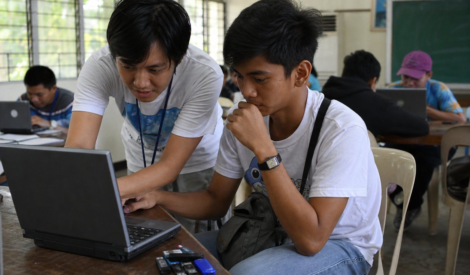 Volunteer helping a student install software on a laptop at a campus install-fest